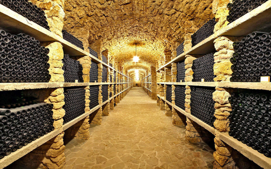 A long stone wine cellar lined with racks of bottles