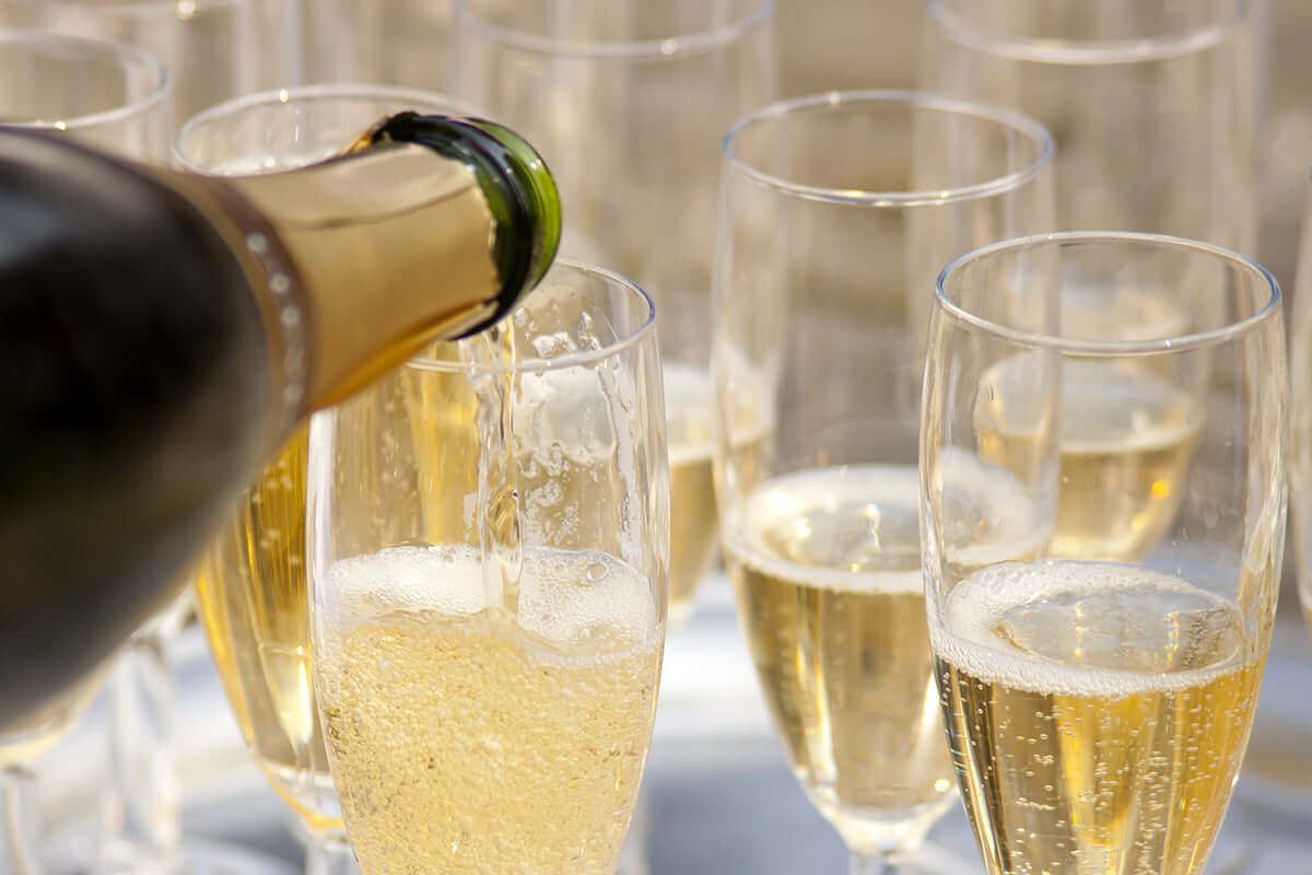 Champagne being poured into a row of flutes at a party