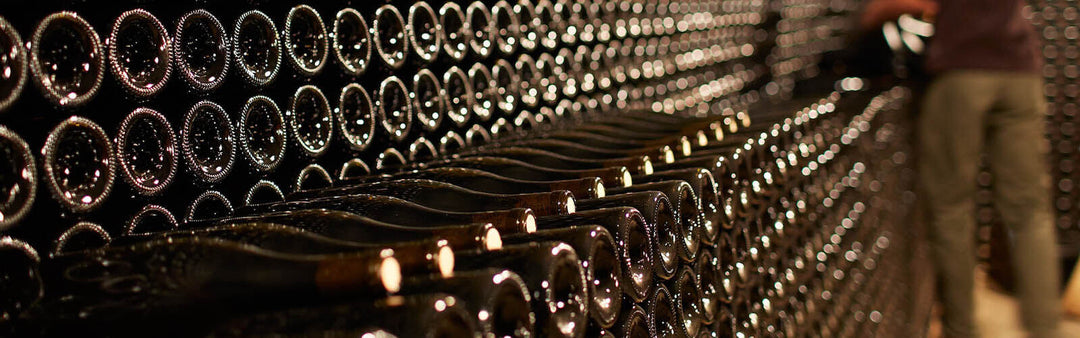 Rows of stacked wine bottles resting in a dimly lit cellar