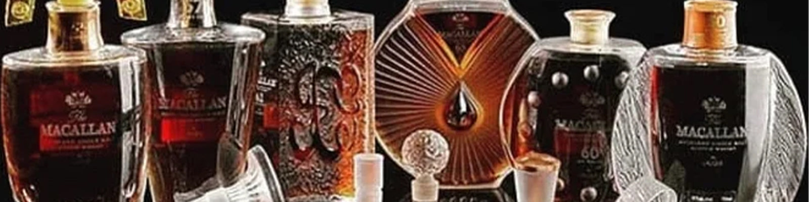 Several ornate bottles of Macallan whiskey with intricate designs and decanter-style tops are displayed in a row against a black background.